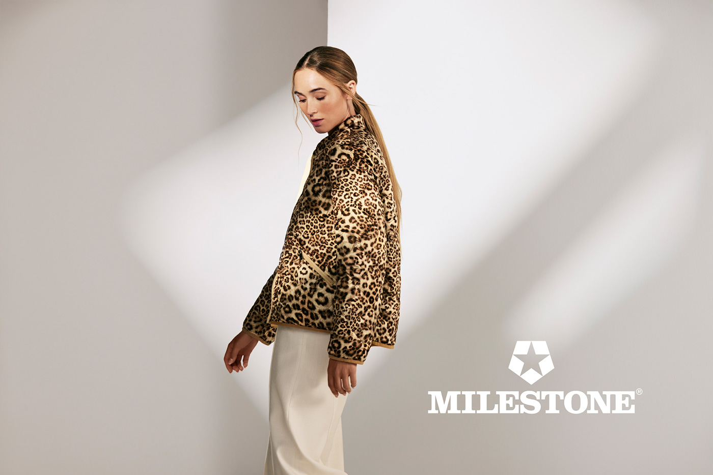 Frau in einer Leojacke vor einer weißen Wand