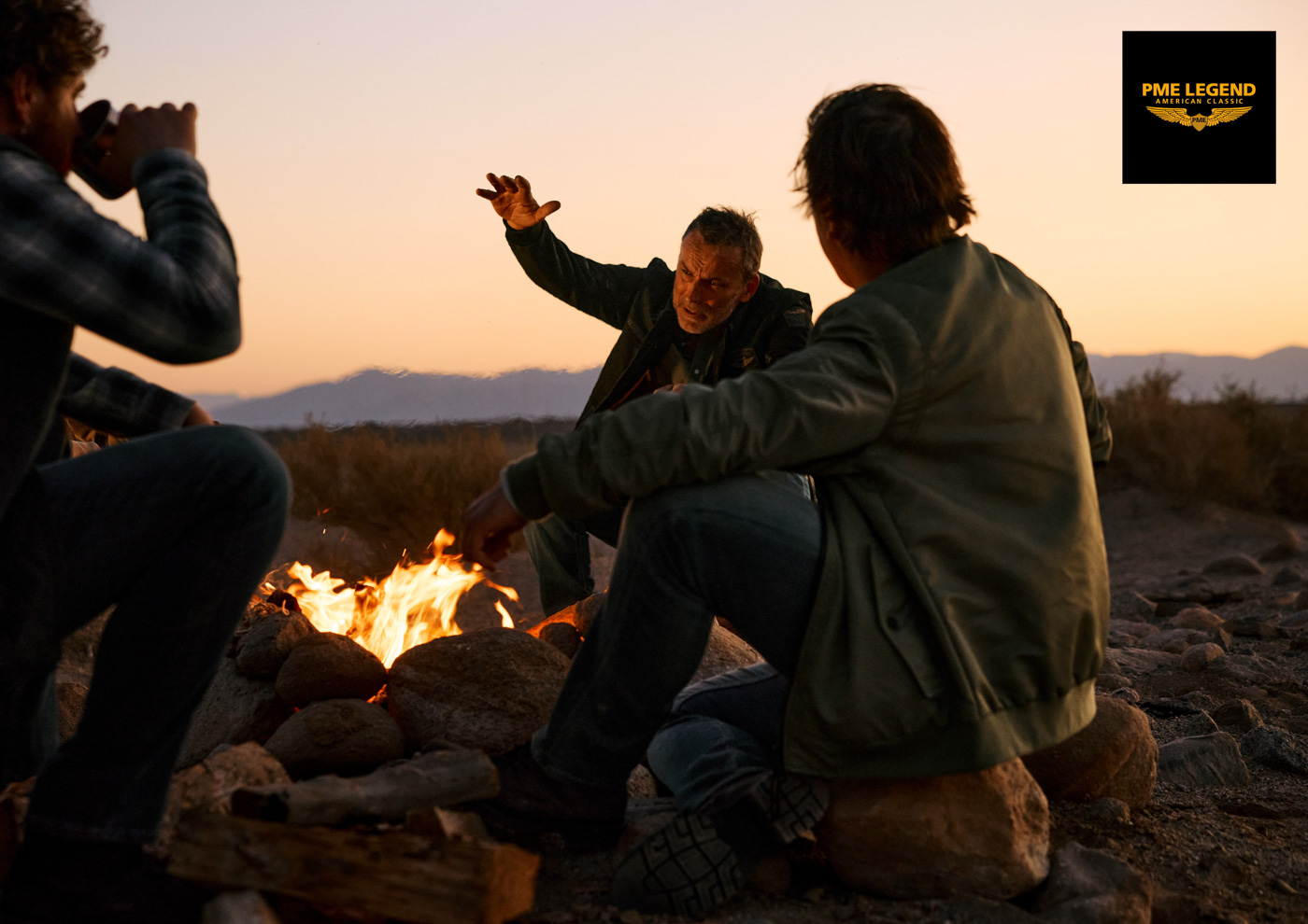 Männer in Herrenmode um ein Lagerfeuer
